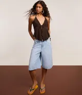 Bermuda jorts de denim color celeste claro, de tiro medio con cinco bolsillos, trabillas para cinturón y cierre frontal con botón y cremallera.
