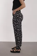 Pantalón negro con estampado de flores rosas y blancas, de corte recto.