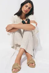 Sandalia plana color beige con tiras cruzadas en la parte delantera.