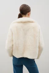 Campera corta de piel sintética en color crema, con cuello amplio tipo solapa y cierre frontal.