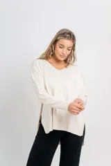 Sweater color crema de punto, con escote en V, corte recto y terminaciones acanaladas en puños y ruedo.