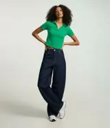 Blusa de cuello polo y manga corta, confeccionada en tejido rib de algodón con elastano. Presenta un diseño ajustado al cuerpo con escote en V y textura acanalada.