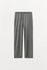 Pantalón de corte recto confeccionado en mezcla de lyocell y lana, con tiro alto y cintura elástica. Presenta detalle de botones a presión en la parte frontal.