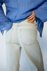 Jeans de tiro medio con corte recto, cinco bolsillos y detalle de rotos. Cierre frontal con cremallera y botón.