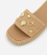 Sandalia plana flatform color beige, con textura trenzada y apliques de colgantes metálicos con motivos marinos.