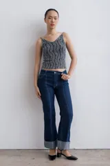 Jean de mezclilla azul oscuro con costuras contrastantes marcadas en el frente y dobladillo ancho vuelto en el ruedo.