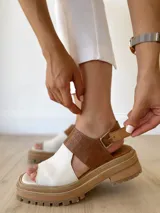 Sandalias de cuero color camel y crudo, con plataforma track y hebilla ajustable.