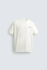 Camiseta de corte relajado, color crudo, con cuello redondo y manga corta. Presenta un pequeño estampado gráfico en el pecho con la inscripción 'Whitsunday Island'.