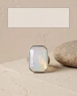 Anillo de acero con piedra central facetada de forma rectangular en tono blanco translúcido.