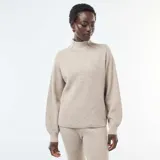 Sweater de punto canalé en color beige, con cuello alto y mangas largas con puños ajustados.