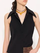 Camisa sin mangas confeccionada en tela de punto lisa, color crema, de corte regular. Lleva cartera con broches JCH y pinzas que entallan la prenda.