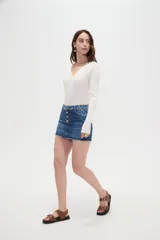 Minifalda de jean azul con cierre frontal de botones metálicos y detalles de estampado animal print en la pretina y los bolsillos superiores. Cuenta con un dobladillo desmechado.