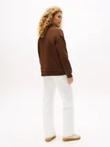 Buzo marrón de felpa con cuello redondo y corte amplio. Estampado frontal con el texto "All American Classics - Tommy Hilfiger" en color crema.