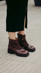 Bota corta de cuero color bordó, con diseño de texturas combinadas, talón texturado y taco geométrico negro.