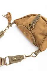 Cartera tipo bandolera de gamuza sintética color marrón, con diseño de media luna, cierre frontal con doble tirador metálico y detalle de borla lateral.