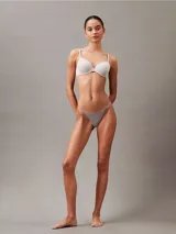 Colaless Calvin Klein Ideal Cotton color gris claro, de talle medio, con laterales y parte trasera de cuerda, y cintura elástica con logo de la marca.