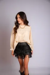 Camisa blanca de manga larga con detalles de encaje o bordado en el canesú y el frente. Presenta un corte holgado y mangas con puños elásticos o fruncidos.