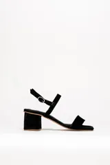 Sandalias de cuero color negro, con taco cuadrado bajo y tira delgada sobre los dedos.