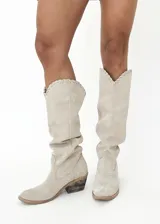 Bota tejana de cuero color beige, con caña alta y detalle de tiento cosido a mano en la parte superior. Tiene taco de 4 cm.