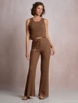 Pantalón de tiro alto con tejido calado y textura labrada, de corte recto con apertura acampanada hacia el ruedo. Cuenta con cintura elastizada y cordón de ajuste con terminaciones de caracoles decorativos.