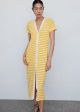Vestido midi de punto con diseño de rayas horizontales amarillas y blancas. Presenta cuello en pico, manga corta y cierre frontal completo con botones. Su diseño es de corte recto.