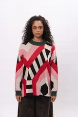 Buzo de tejido de punto con diseño geométrico multicolor en tonos rojo, rosa, negro y beige. Presenta cuello redondo y puños en color verde oscuro.
