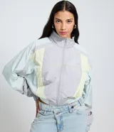 Campera corta viento de mujer de la marca Blue Steel, con cuello alto, mangas largas con puños elásticos y cierre frontal por cremallera. Presenta recortes contrastantes en tonos gris, celeste y amarillo pastel, y ruedo corto con elástico. Confeccionada en poliamida, un tejido sintético ligero y suave.