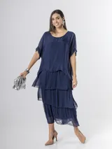 Vestido largo azul marino de seda italiana, con diseño de volados escalonados en la falda y una sobrecapa superior con mangas cortas amplias.
