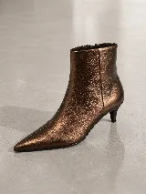 Bota de cuero con acabado metalizado color bronce, de punta fina y taco fino de altura media. Presenta un diseño minimalista con cierre lateral interno.