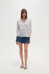 Camisa de algodón con diseño de rayas verticales y detalles bordados. Presenta cuello en V, cierre frontal con botones y mangas tres cuartos con terminación elástica.