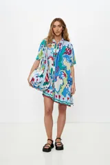 Bolso tote de tela estampada con motivos florales y geométricos en tonos azul, verde, rojo y blanco. Tiene doble asa de hombro y cierre con cordón ajustable con cuentas de madera.