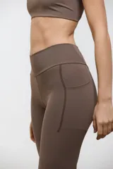 Calza deportiva larga de tiro alto, con bolsillos laterales integrados. Confeccionada en tejido elastizado de compresión media, con diseño liso y corte al tobillo.