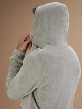 Campera con capucha de toalla color gris claro, con cierre completo y bolsillos frontales.