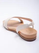 Sandalia baja de símil cuero color marrón, con doble cinta ancha cruzada sobre el empeine y tira elástica para ajuste en el tobillo.