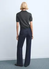 Pantalón de jean de corte recto y tiro medio, en color azul oscuro con costuras en contraste. Presenta cierre frontal con botón y bolsillos laterales y traseros.
