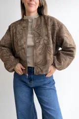 Campera bomber de corte oversize con cierre frontal metálico, mangas globo y diseño con bordados florales en toda la superficie.