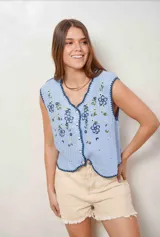 Chaleco celeste tejido de punto con diseño de flores bordadas, escote en V y cierre frontal con botones claros. Presenta detalles de terminación festoneada en tono azul oscuro.