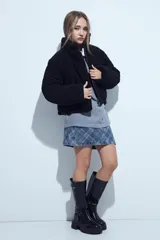 Campera puffer de corderito negro con cuello alto y diseño oversized. Presenta una textura tipo teddy, cierre frontal y corte a la cintura.