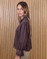 Blusa blanca de algodón con escote en V y cuello mao. Presenta mangas largas abullonadas con puños acampanados y fruncidos.