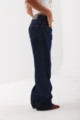 Pantalón de jean corte wide leg color marrón oscuro, con tiro medio y cierre frontal con botón metálico.