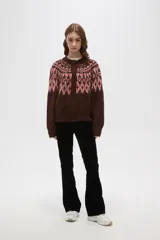 Cardigan de tejido jacquard con diseño geométrico en la parte superior, cuello redondo y cierre frontal con botones. Presenta un corte holgado y mangas largas con puños acanalados.