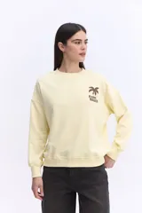 Buzo de algodón color lila, de calce relajado y hombros caídos, con estampa pequeña en el frente que dice "Palm Beach" y una palmera.