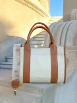 Cartera tote de cuero color crema con detalles en cuero color suela, doble asa corta y correa larga de cuero con estampado animal print.