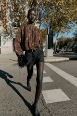 Falda pantalón negra de tiro medio con cierre frontal y hebilla metálica. Presenta bolsillos delanteros y falsos bolsillos de vivo en la espalda.