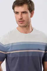 Remera de manga corta con diseño de franjas horizontales en tonos de gris, azul y beige, con escote redondo y pequeño bordado en el pecho.