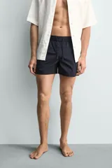 Short de baño de color azul marino, confeccionado en tejido técnico, con cintura elástica ajustable mediante cordón, bolsillos laterales y detalle de bolsillo trasero.