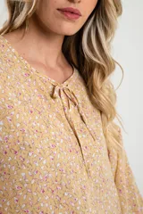 Blusa amarilla con estampado floral, cuello redondo con lazo y mangas largas abullonadas.