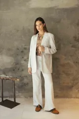 Pantalón sastrero de corte recto y tiro medio, confeccionado en tejido de lino con destellos de lurex, con cierre frontal y trabillas para cinturón.