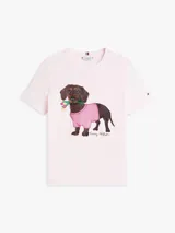 Remera de manga corta color rosado de Tommy Hilfiger, con cuello redondo y diseño casual. En el centro del pecho cuenta con un gráfico bordado de un perro salchicha con un suéter a cuadros rosado y blanco, y flores en la boca.