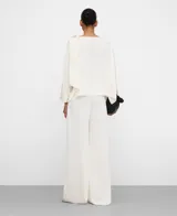 Pantalón palazzo satinado de color blanco, de corte ancho y tiro medio, con cierre de cremallera invisible en el costado.